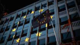 Proyección de la bandera europea sobre una fachada, junto a la propia bandera de la UE.