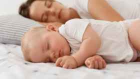 Un bebé y su madre durmiendo en una imagen de archivo.