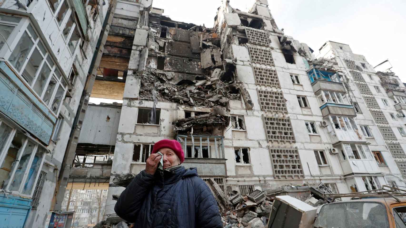 Una mujer y su bloque residencial en Mariúpol.