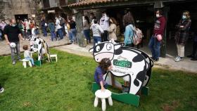 Varias personas compran productos lácteos, mientras unos niños juegan a ordeñar, en el Xanceda Market , en la granja Casa Grande de Xanceda.
