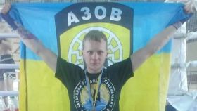 Maksym Kagal posando con la bandera del Batallón Azov