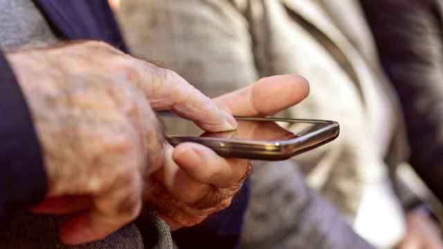 Un hombre pulsa la pantalla de un teléfono móvil con su dedo.