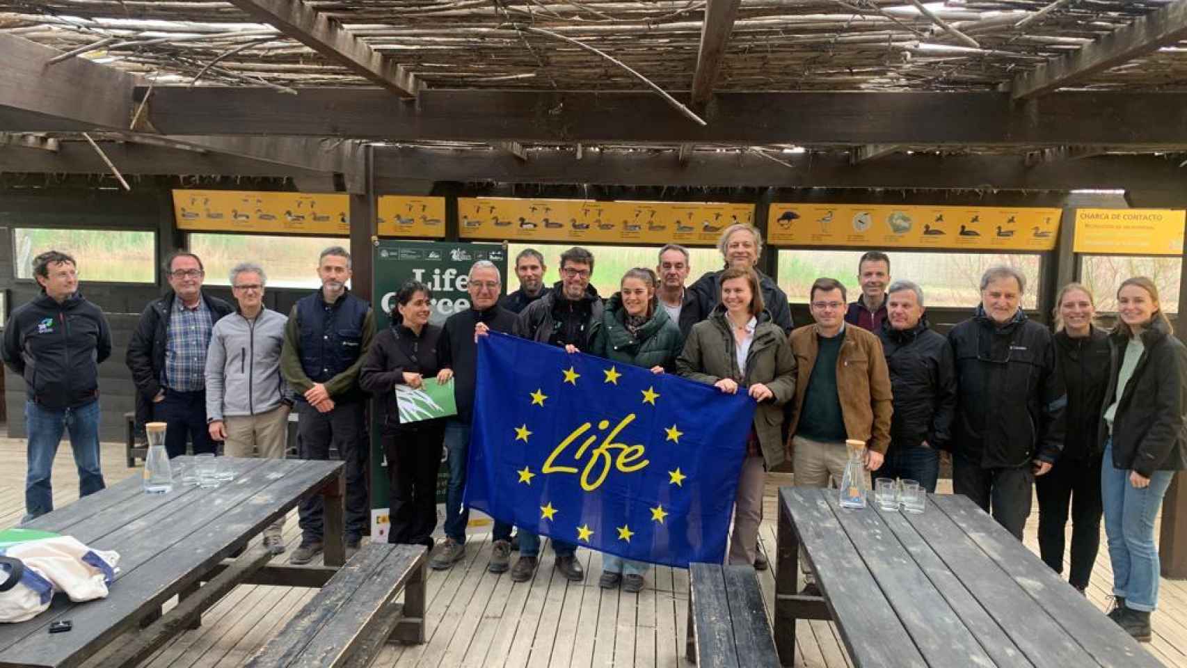 Un grupo de integrantes del proyecto LIFE Cerceta Pardilla sostiene una bandera de la Unión Europea