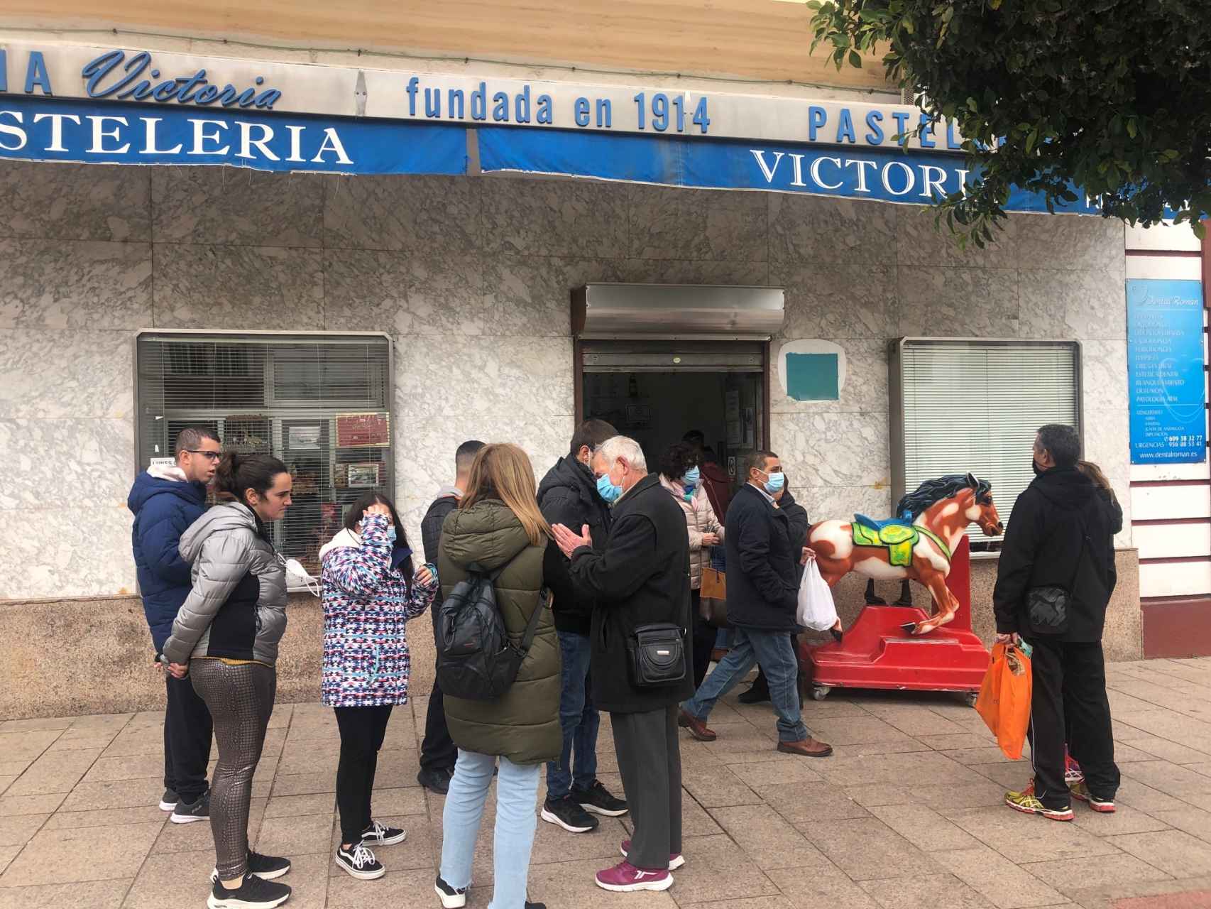 La gente espera en la puerta, haciendo cola, para comprar en la Pastelería La Victoria.