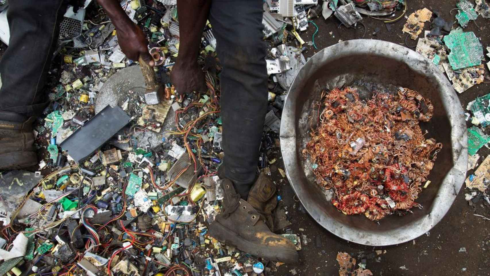 Un hombre rescata hilos de cobre de entre restos de aparatos tecnológicos en el vertedero de Agbogbloshie.