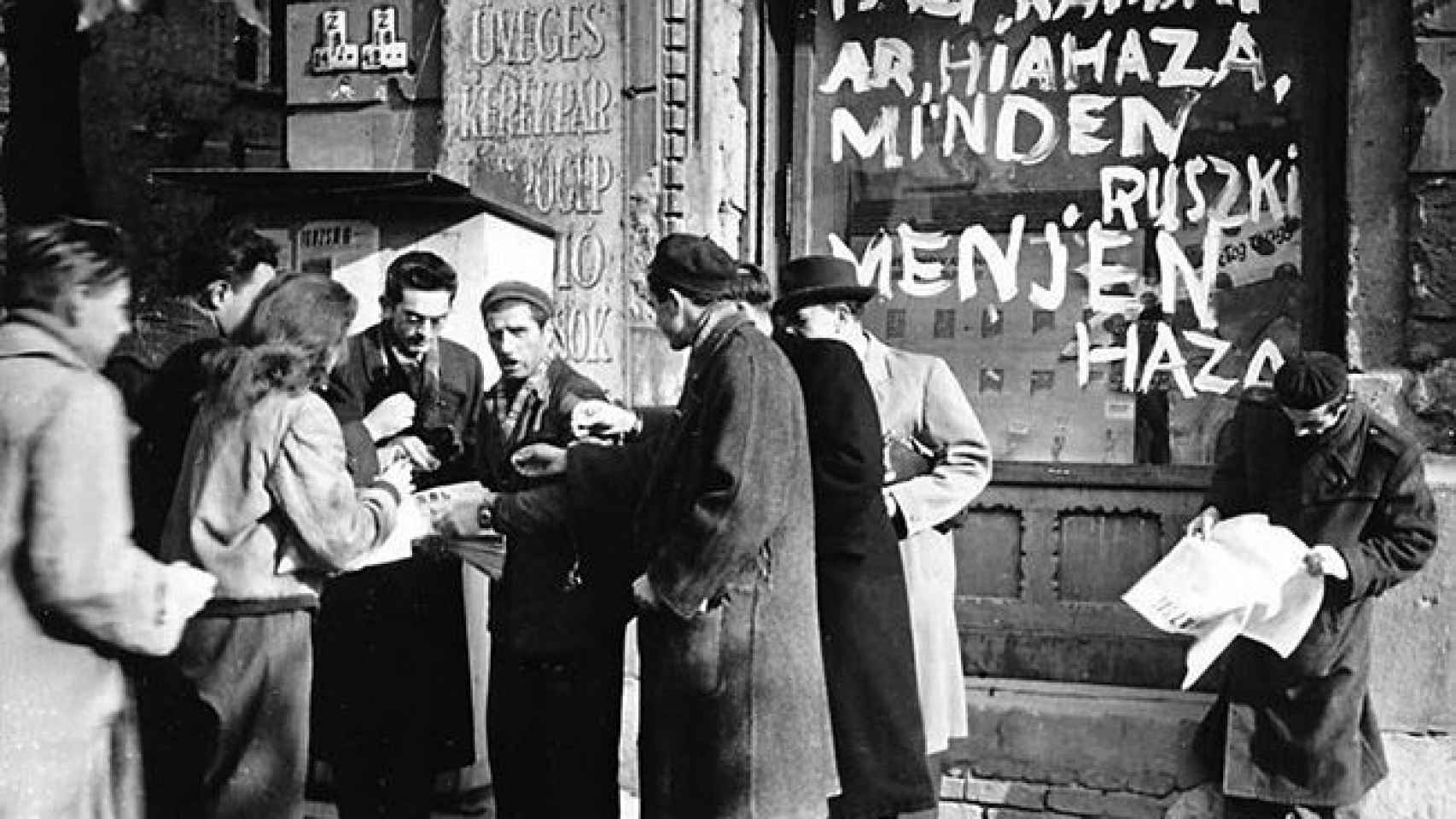 Un grupo de húngaros delante de un escaparate con la inscripción ¡Rusos, volved a vuestro país!, en 1956, en Budapest.
