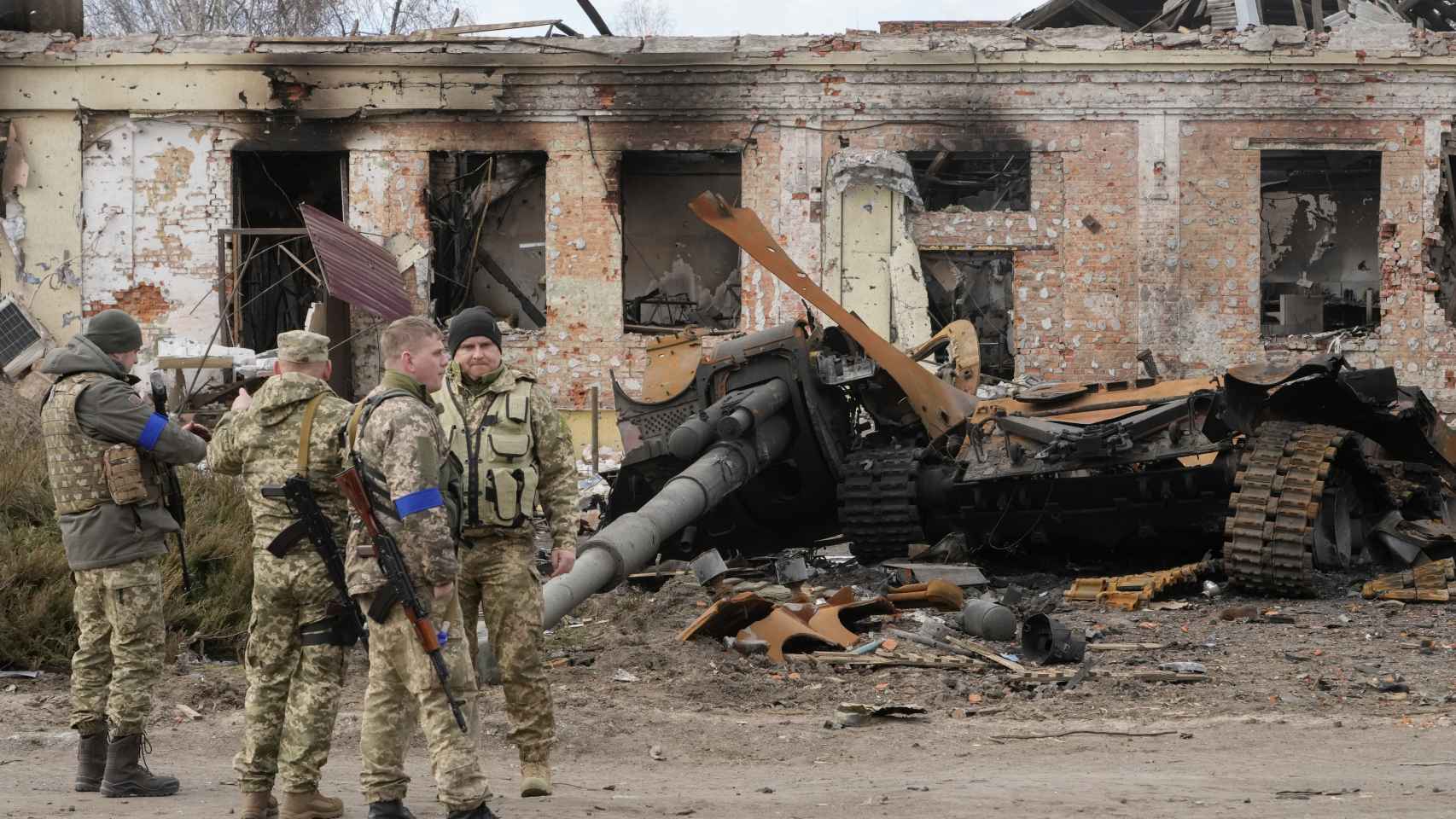 Soldados ucranianos contemplan un tanque ruso destruido.