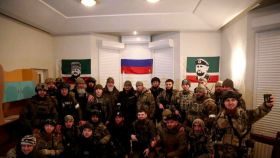 Grupo de chechenos posando junto a una bandera rusa.