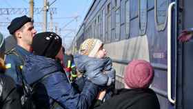 Una mujer ayuda a un niño a subirse a un tren en Ucrania. Foto: Andriy Andriyenko.