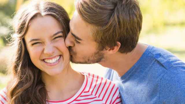 Un hombre dándole un beso en la mejilla a su pareja.