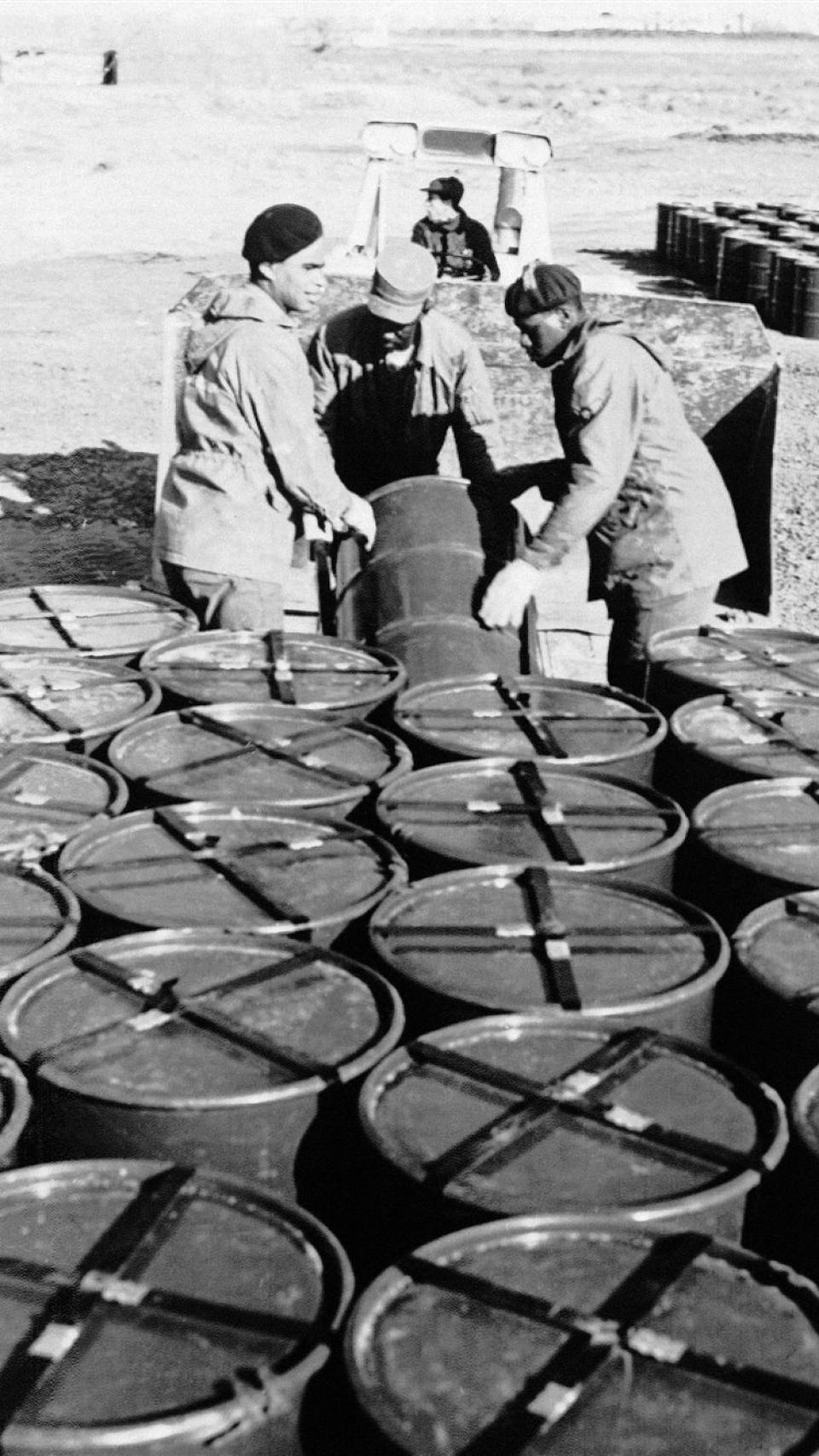Militares estadounidenses, con los barriles de tierra contaminada.