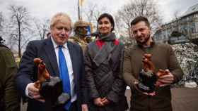 Boris Johnson y Volodimir Zelenski posan con la mujer que les ha regalado unos gallos de cerámica.