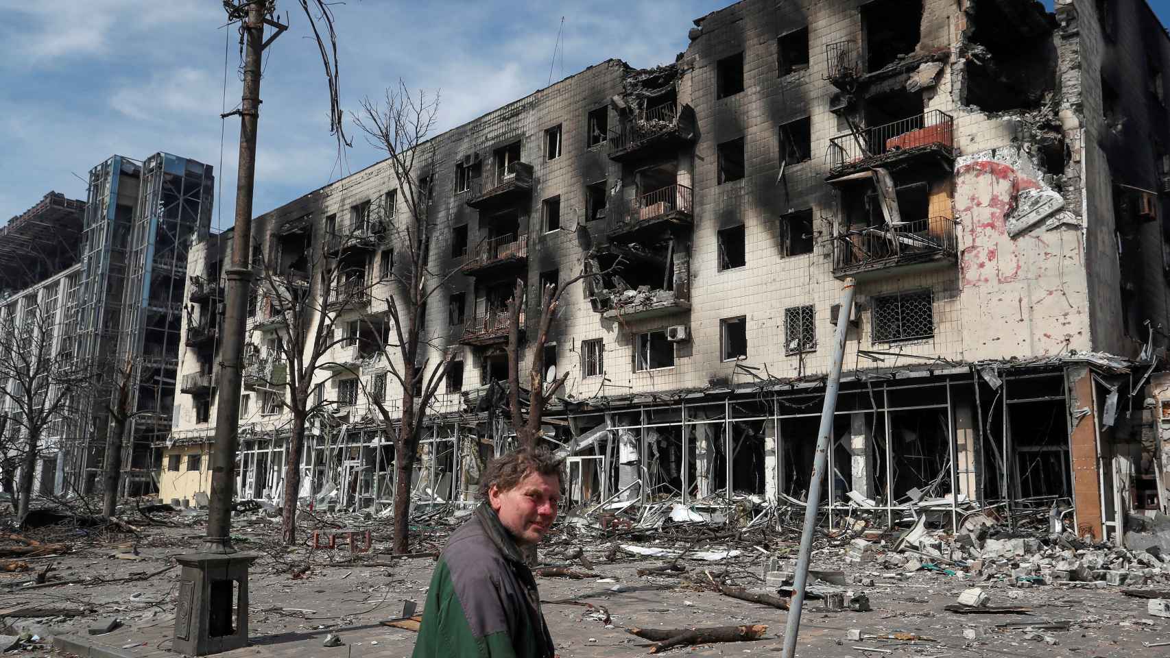 Un ciudadano ucraniano camina ante edificios destrozados por los bombardeos rusos.