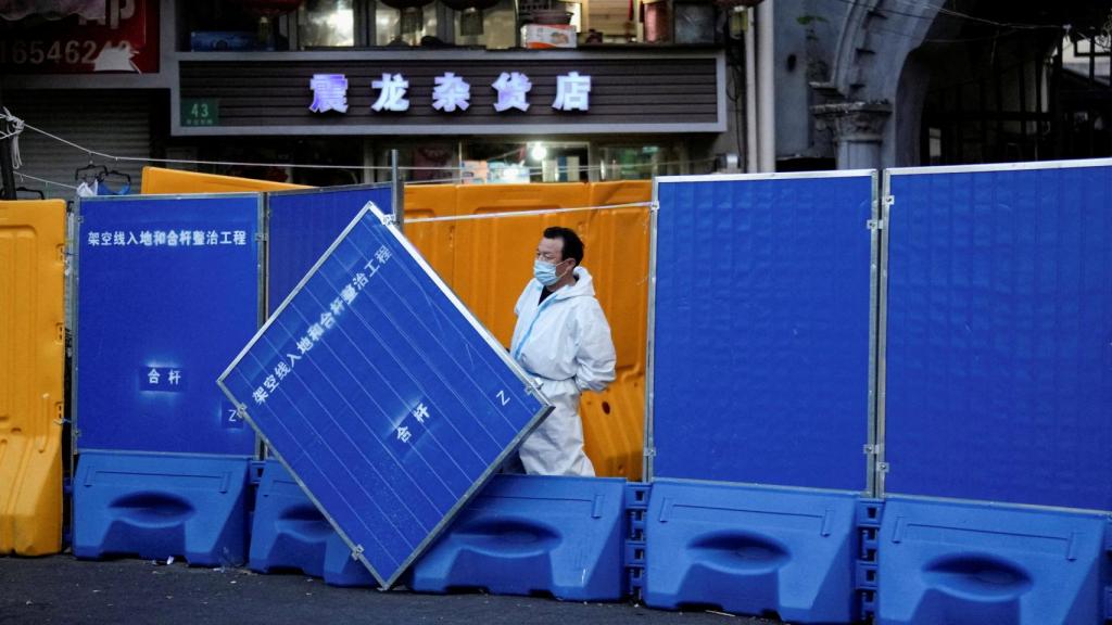 Un trabajador con traje protector vigila junto a las barricadas en un área sellada por la Covid-19 en Shanghái, China.