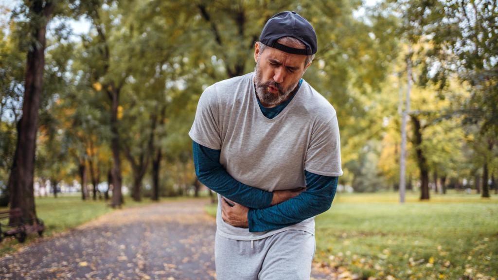 Un hombre siente un dolor de tripa mientras hace deporte.