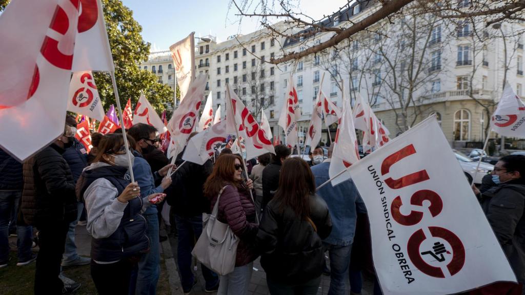 Varias personas con banderas de distintos sindicatos, participan en una concentración para denunciar el bloqueo de la negociación del convenio sectorial del Contact Center, en la Plaza de la Lealtad, a 22 de febrero de 2022, en Madrid (España).