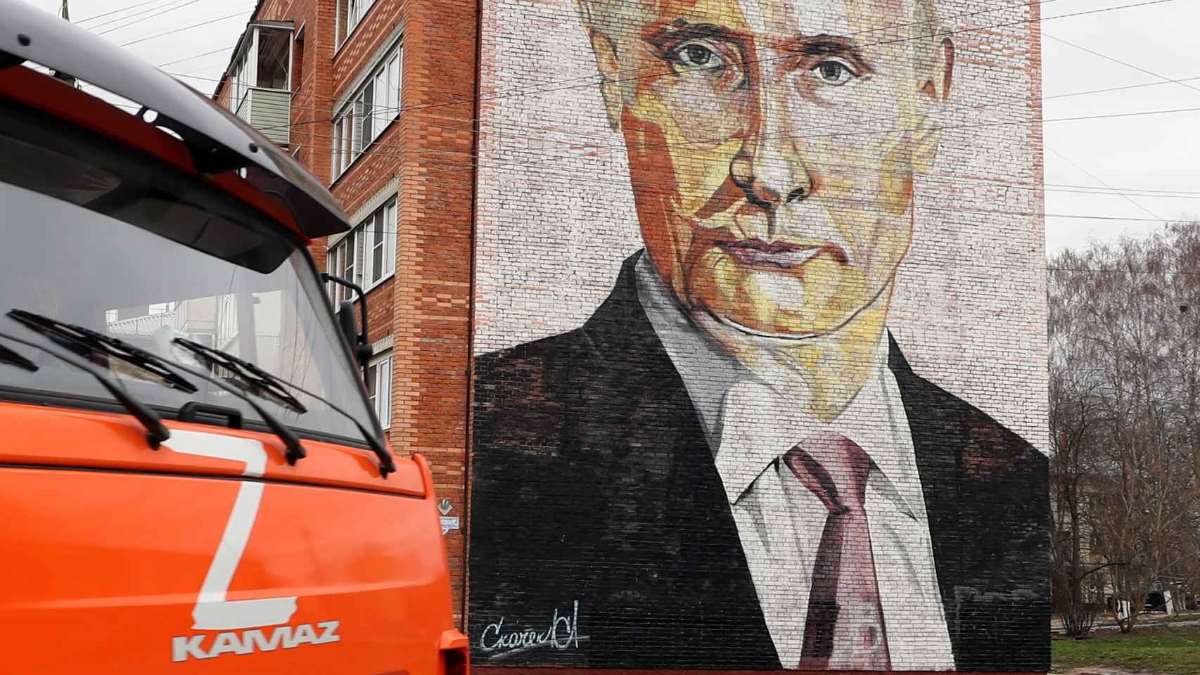 Un camión con la letra Z circula por una calle frente a un bloque de pisos con un mural que representa al presidente ruso Vladimir Putin en la ciudad de Kashira, Rusia.