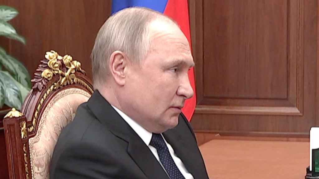 Vladimir Putin, sujetándose a la mesa en una reunión televisada.
