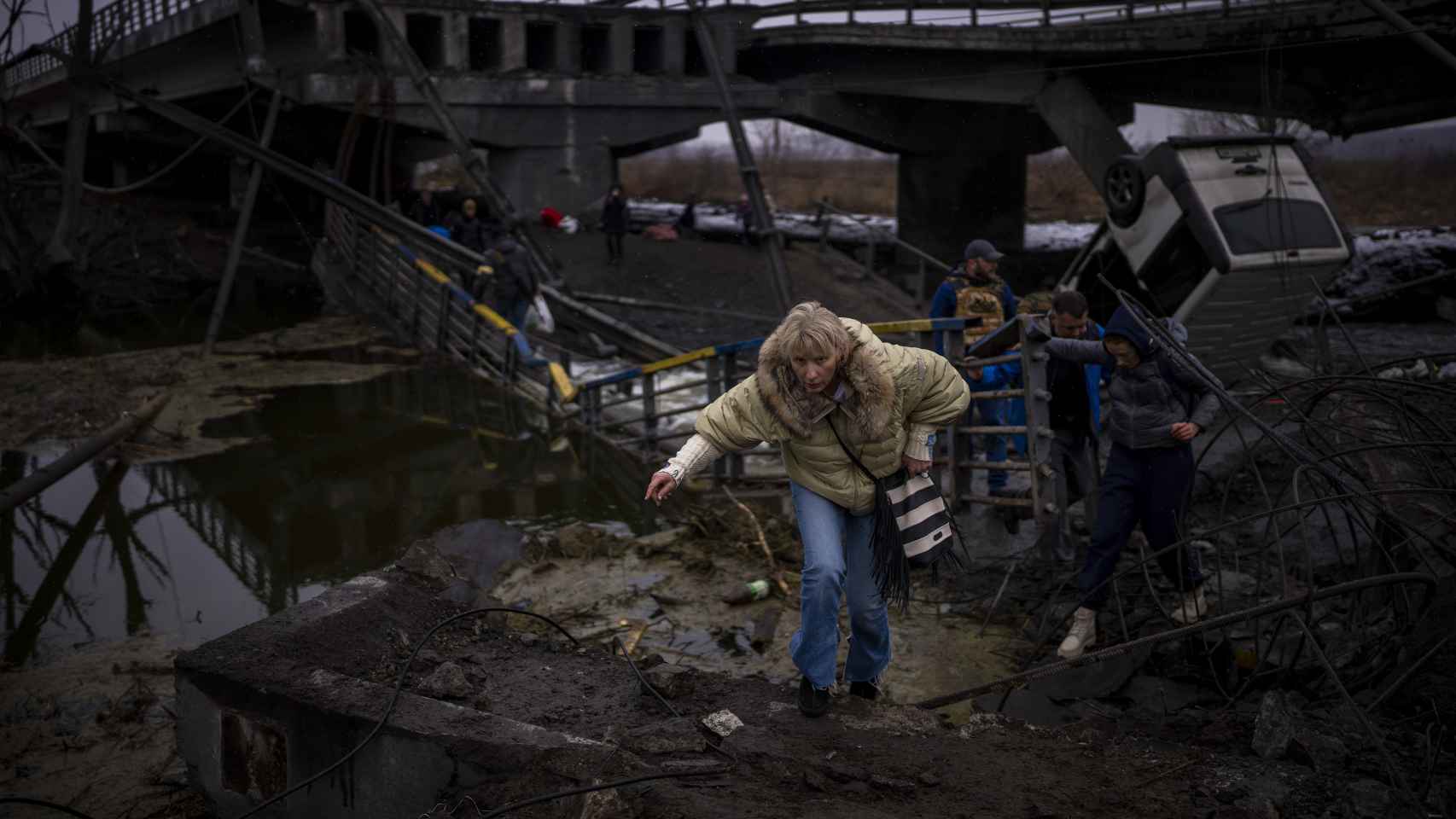Una mujer huye con su familia a través de un puente destruido en las afueras de Kiev, Ucrania.