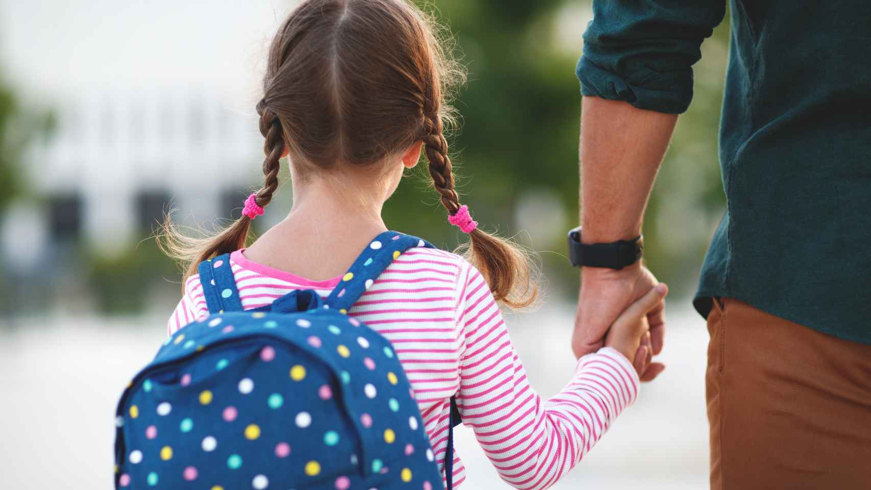 Imagen de archivo de una niña de camino al colegio junto a su padre.