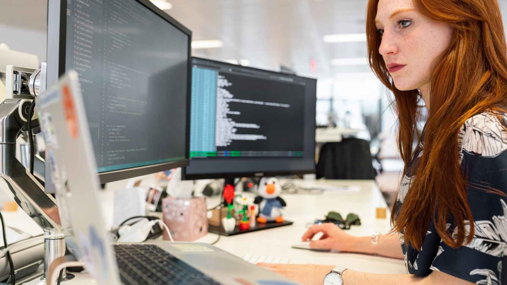 Una mujer utilizando varios ordenadores en su trabajo.