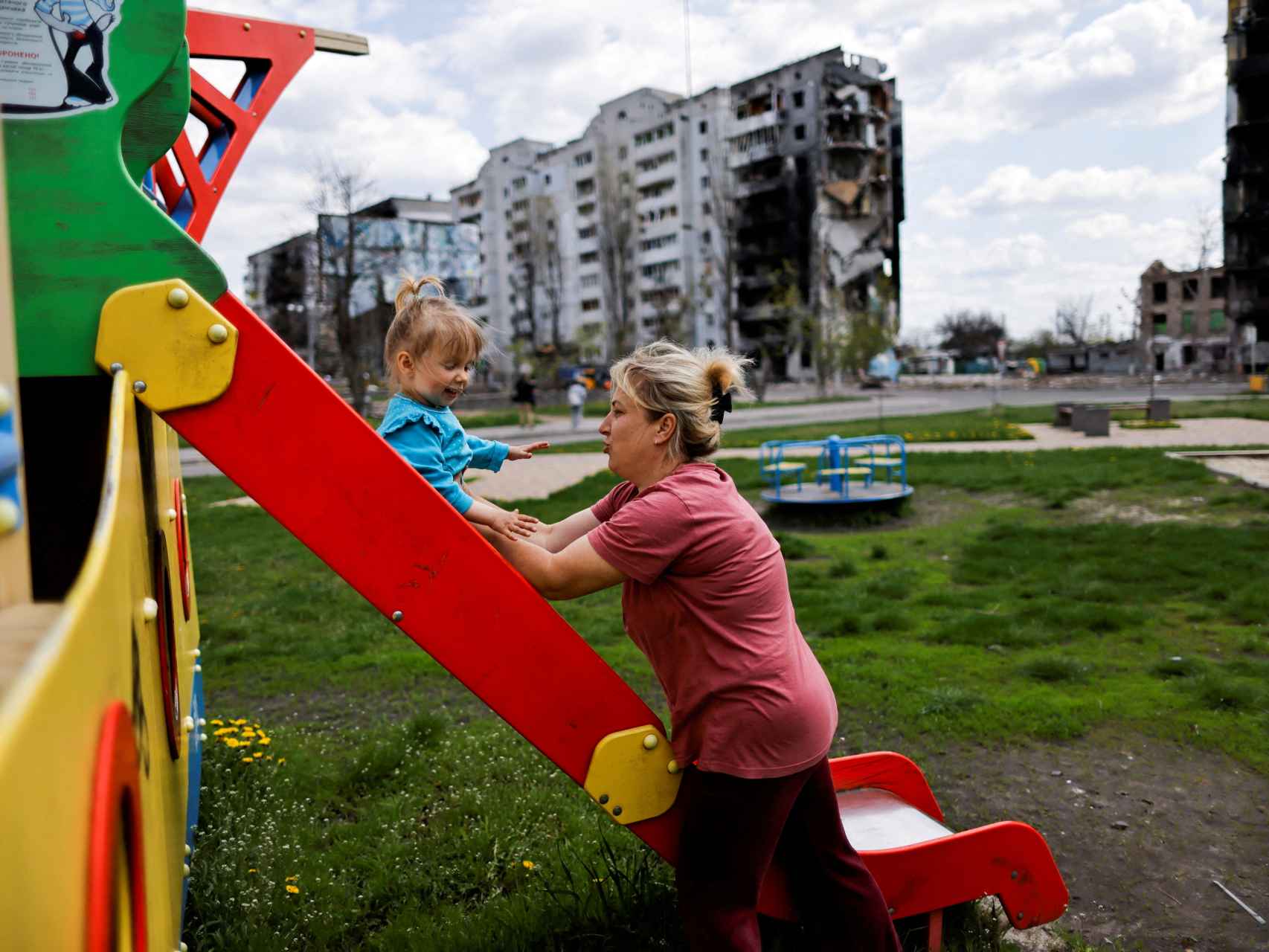 Inna juega con su hija frente a un edificio destruido por los bombardeos en Borodianka.