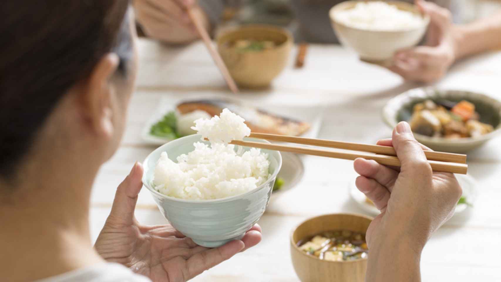 Una persona comiendo arroz blanco al estilo japonés.