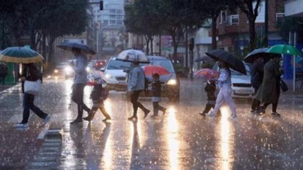 Imagen de archivo de un grupo de personas que se protege de la lluvia.