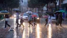 Imagen de archivo de un grupo de personas que se protege de la lluvia.