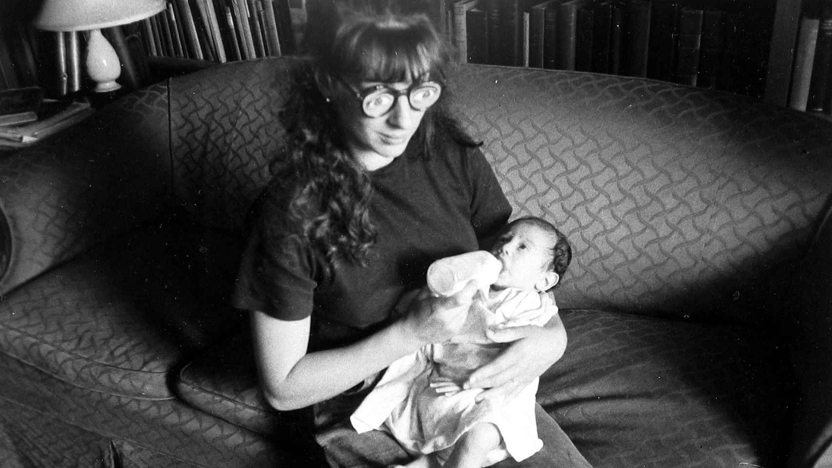 Robert Frank: 'Mary lleva unas gafas falsas mientras  da el biberón a Pablo en el sofá', h. 1951. © Andrea Frank Foundation