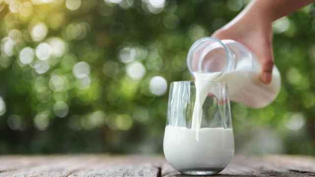 Echando leche de la botella a un vaso.