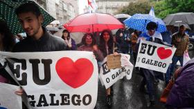 Varias personas con paraguas y carteles en la manifestación.