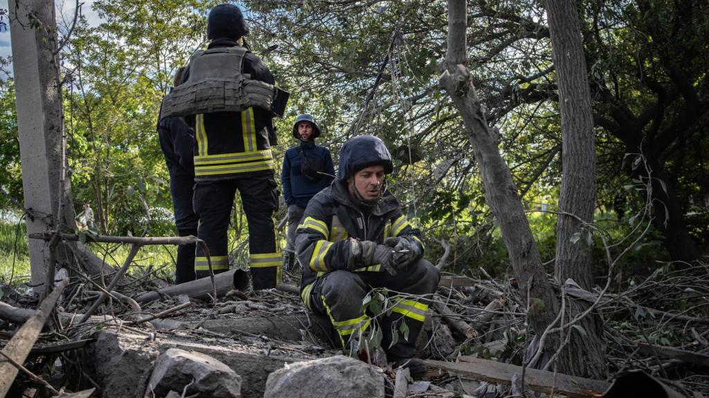 Un bombero descansa junto al fuego con un cigarro en la mano. Ahora también trabajan con chalecos antibalas.