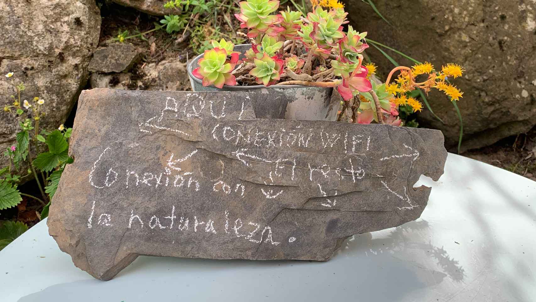 La piedra y el mensaje que reciben al visitante a la entrada al jardín de Apartamentos Buenamadre