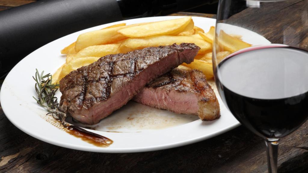 Rodajas de carne roja poco hecha y una copa de vino.