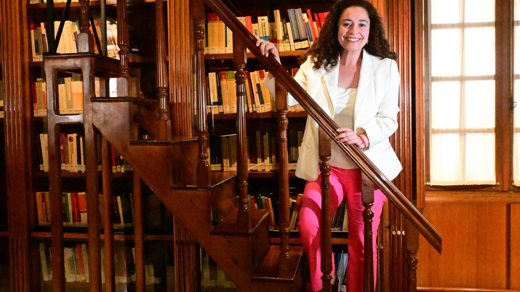 La candidata de la coalición de izquierdas, en la escalera que da acceso a los libros más altos de la biblioteca.