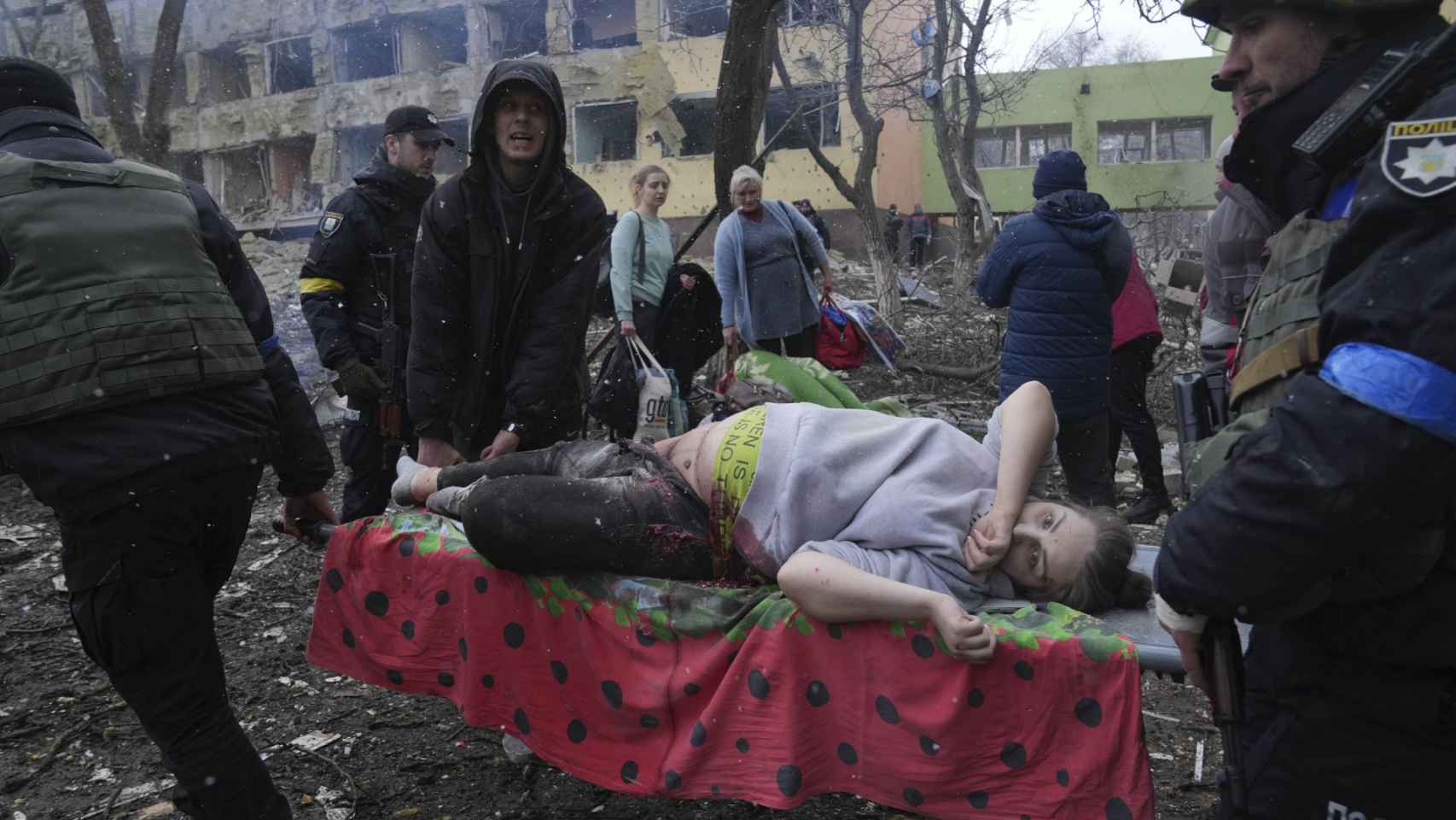 Empleados y voluntarios de emergencia ucranianos llevan a una mujer embarazada herida desde el hospital de maternidad destruido por los bombardeos en Mariúpol, Ucrania, el  9 de marzo .