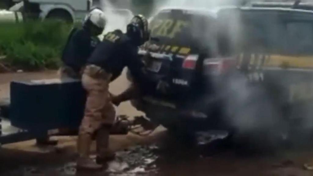 Los dos policías gaseando al hombre dentro del maletero del coche.