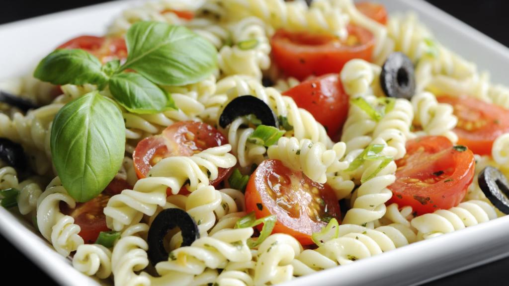 Una ensalada de pasta con tomates y aceitunas.