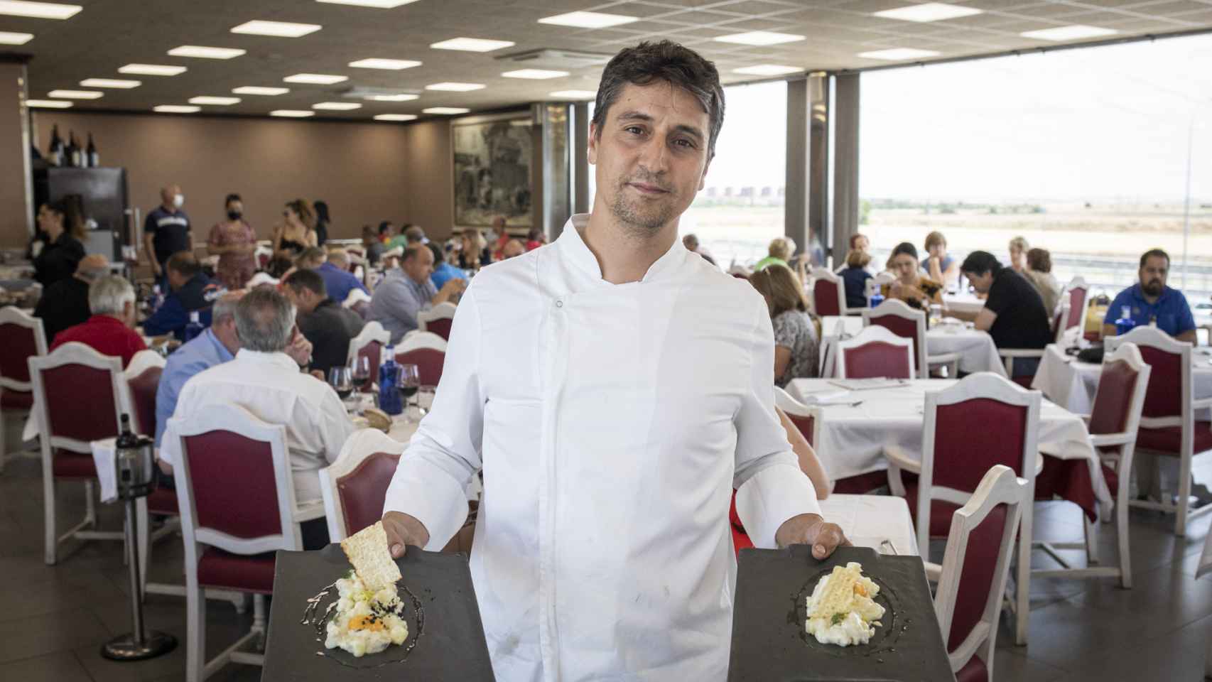 El chef Álex Rey, sujetando dos platos a la hora de la comida en el restaurante Desguaces La Torre.