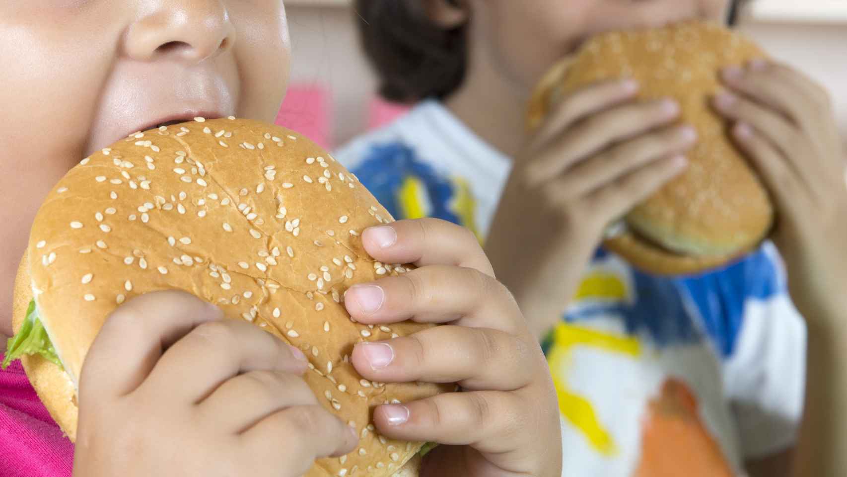 Dos niños comiendo hamburguesas.