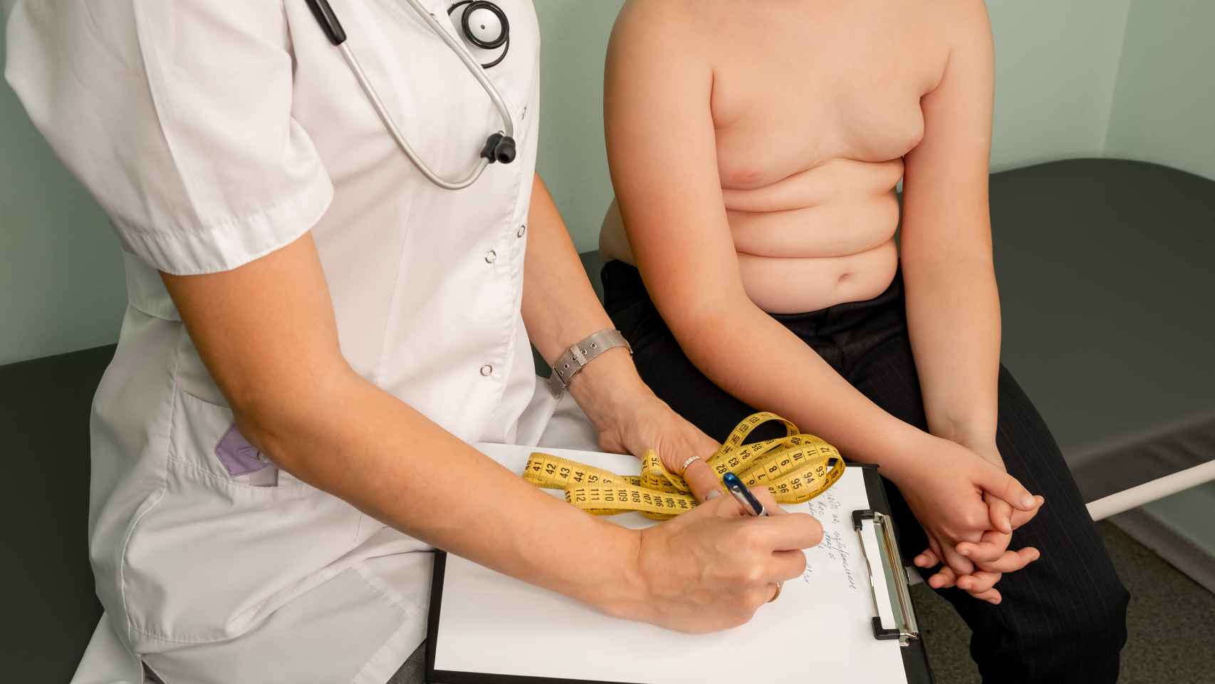Un médico hace un chequeo a un niño con sobrepeso.