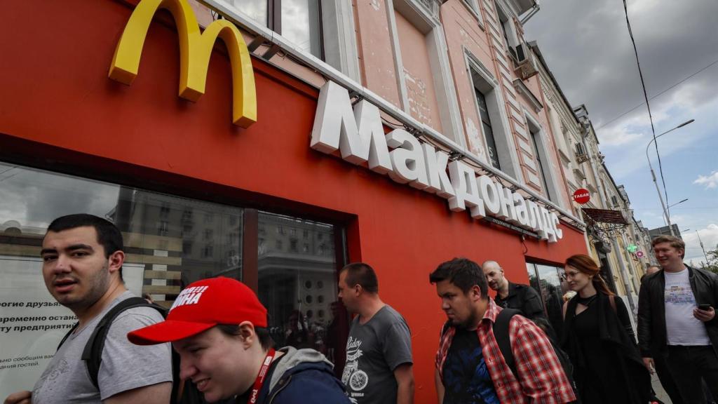 Personas pasan delante de un establecimiento de comida rápido cerrado en Moscú.