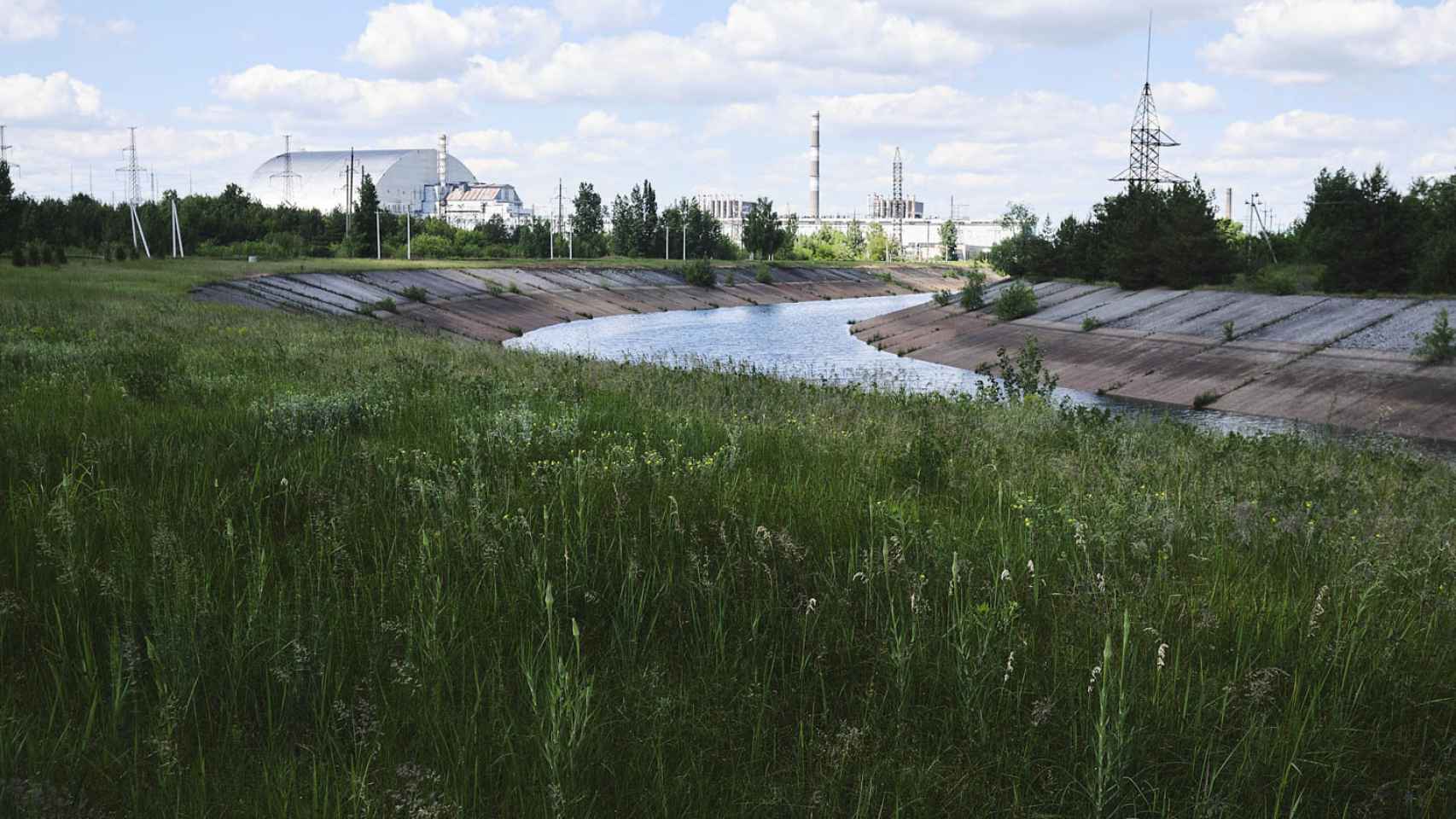 El sarcófago, al fondo, que encierra el accidentado reactor 4 de Chernóbil, junto al canal de refrigeración de la central nuclear, que sigue en activo.