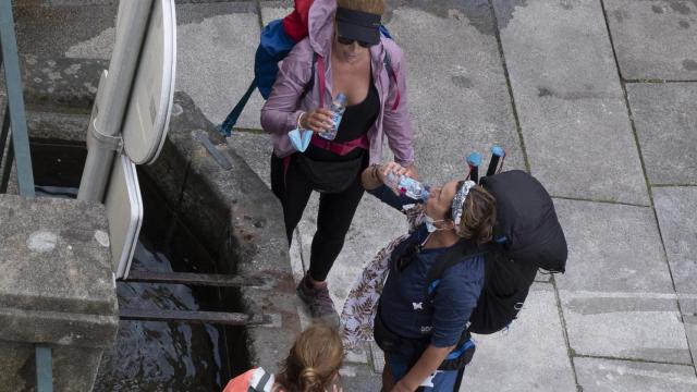 Tres peregrinas beben agua en una fuente en Santiago de Compostela.