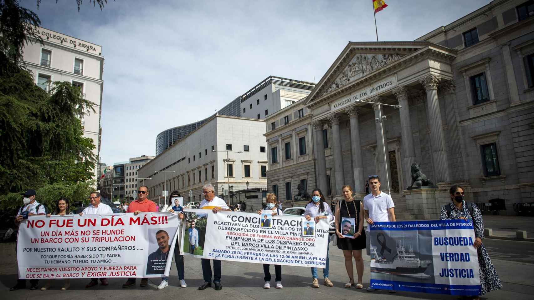 Familiares de marineros fallecidos sostienen pancartas y fotografías en una concentración, a las puertas del Congreso de los Diputados.