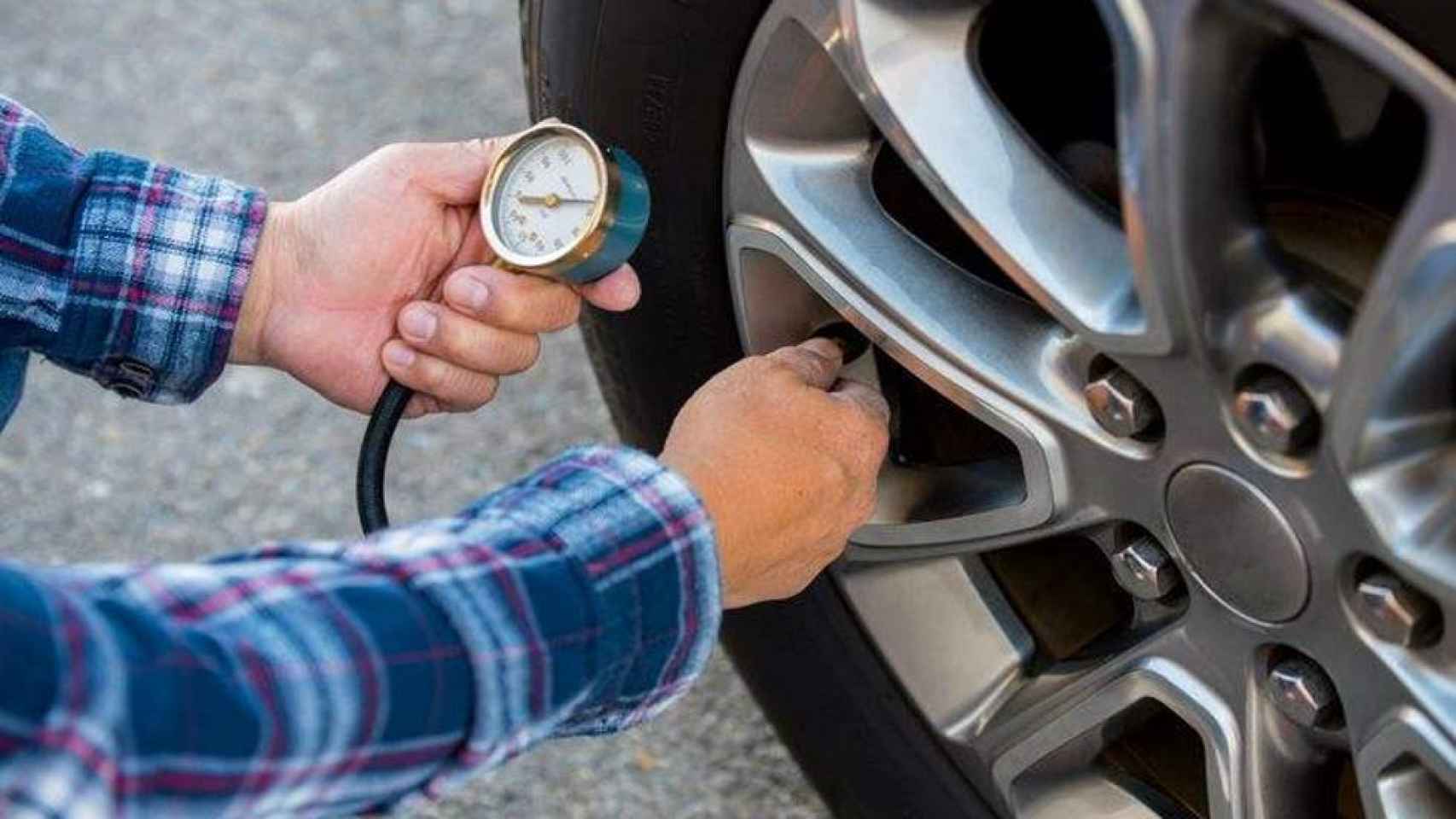 Una persona revisando los neumáticos de su coche.
