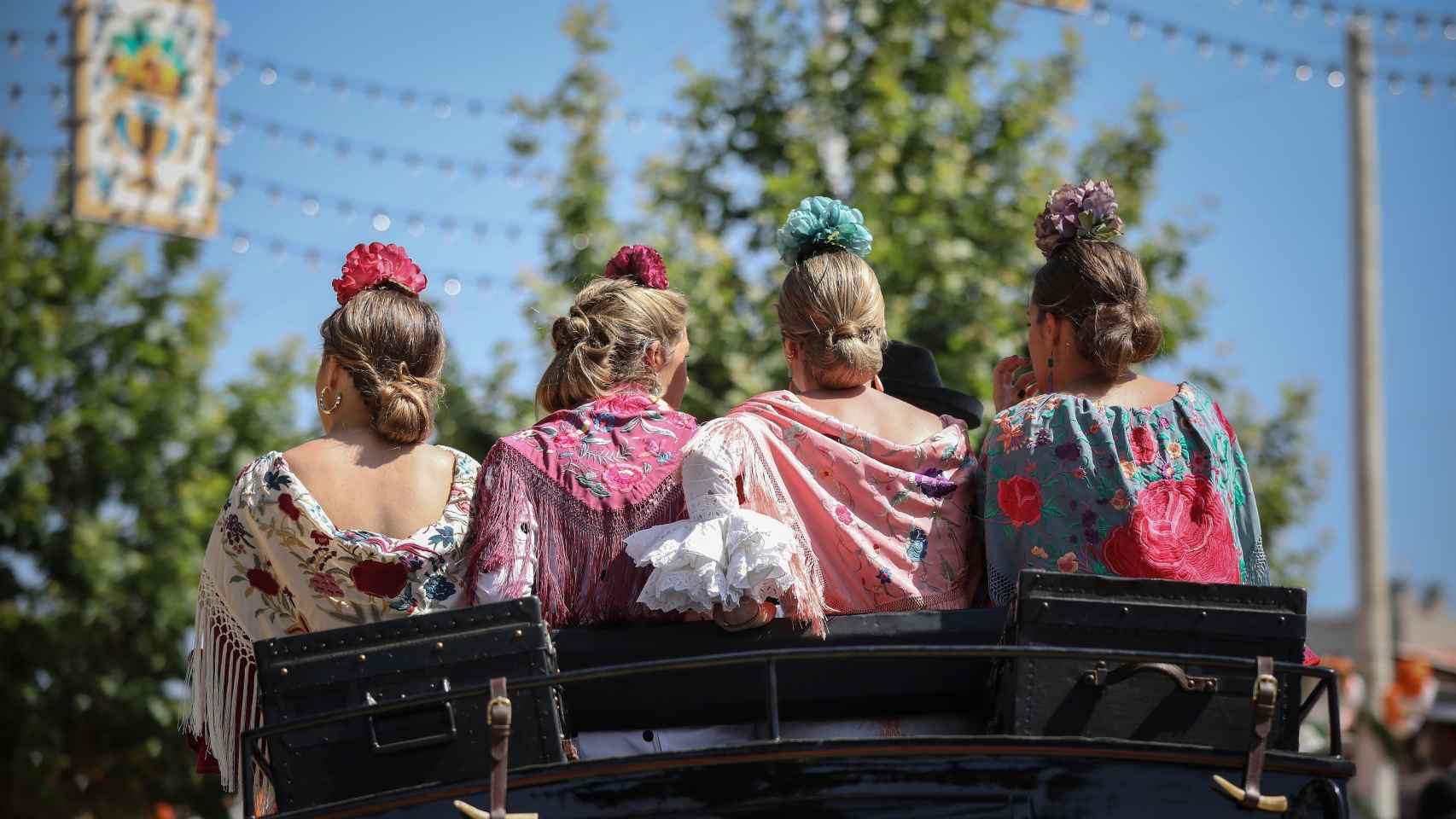 Flamencas con mantones bordados pasean por el real en coche de caballo en la Feria de  Abril de 2019.