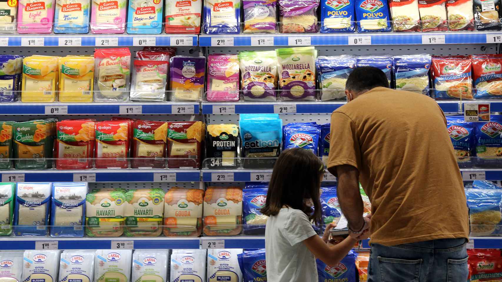 Un padre mira los precios de los alimentos en un lineal de un supermercado