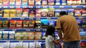 Un padre mira los precios de los alimentos en un lineal de un supermercado